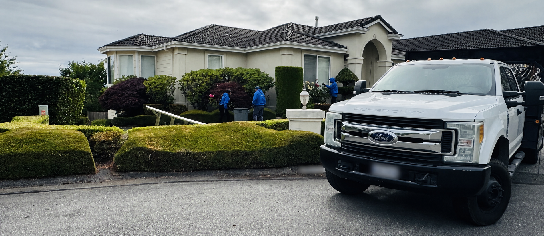 Crew trimming hedges at a home, with the company truck parked out front