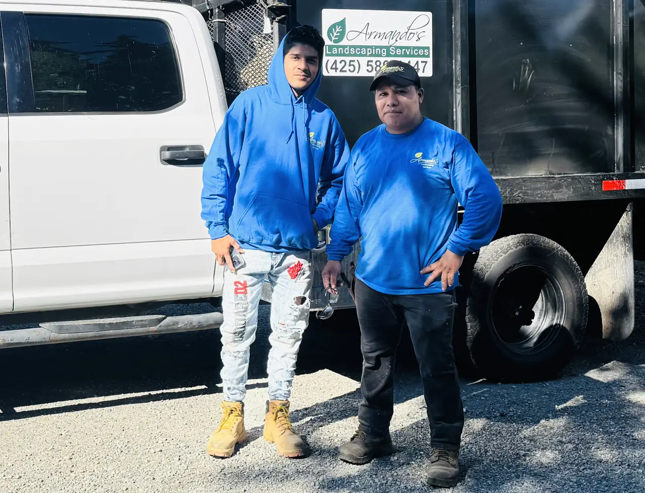 Two crew members in a company hoodie and shirt beside the work truck