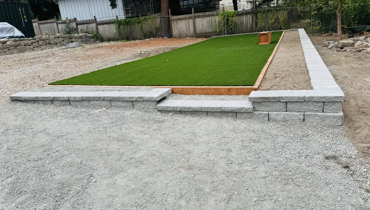 Low block wall and gravel finished around an artificial turf area in the same yard